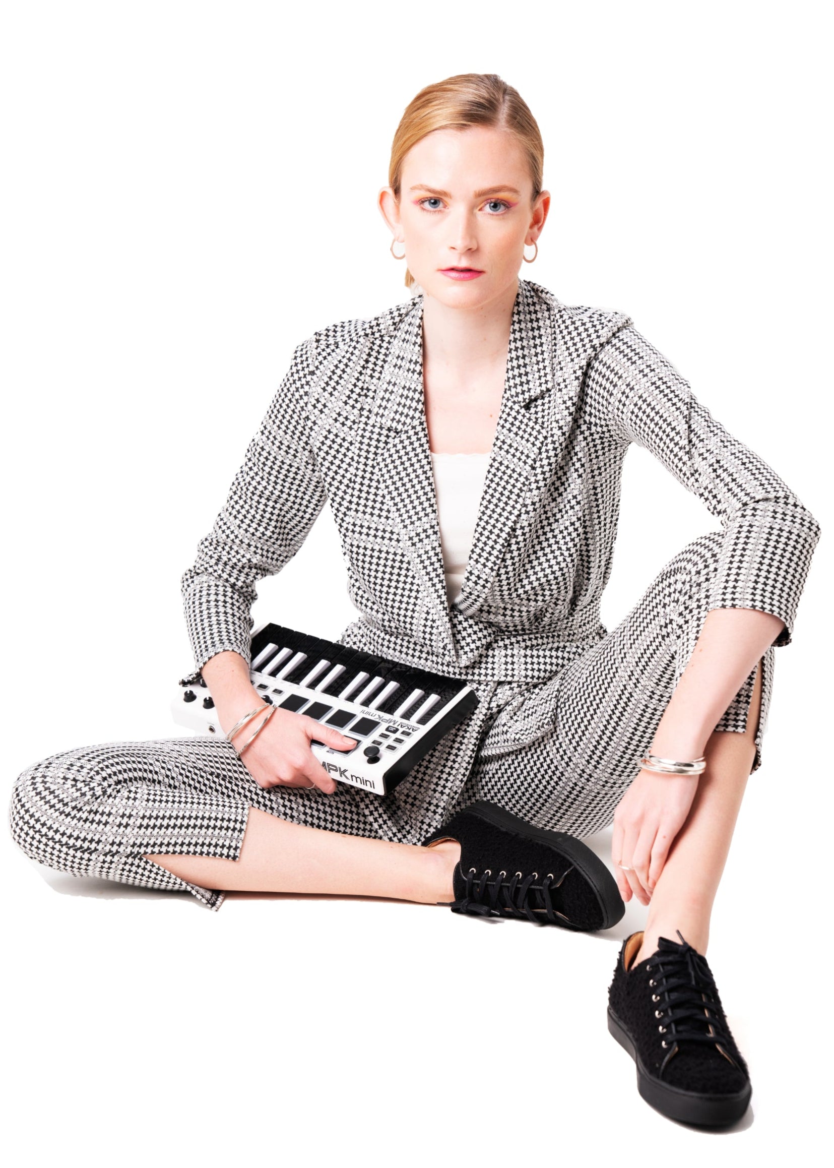 Woman in a checkered outfit with black Casetino shoes holding a clutch on a white background
