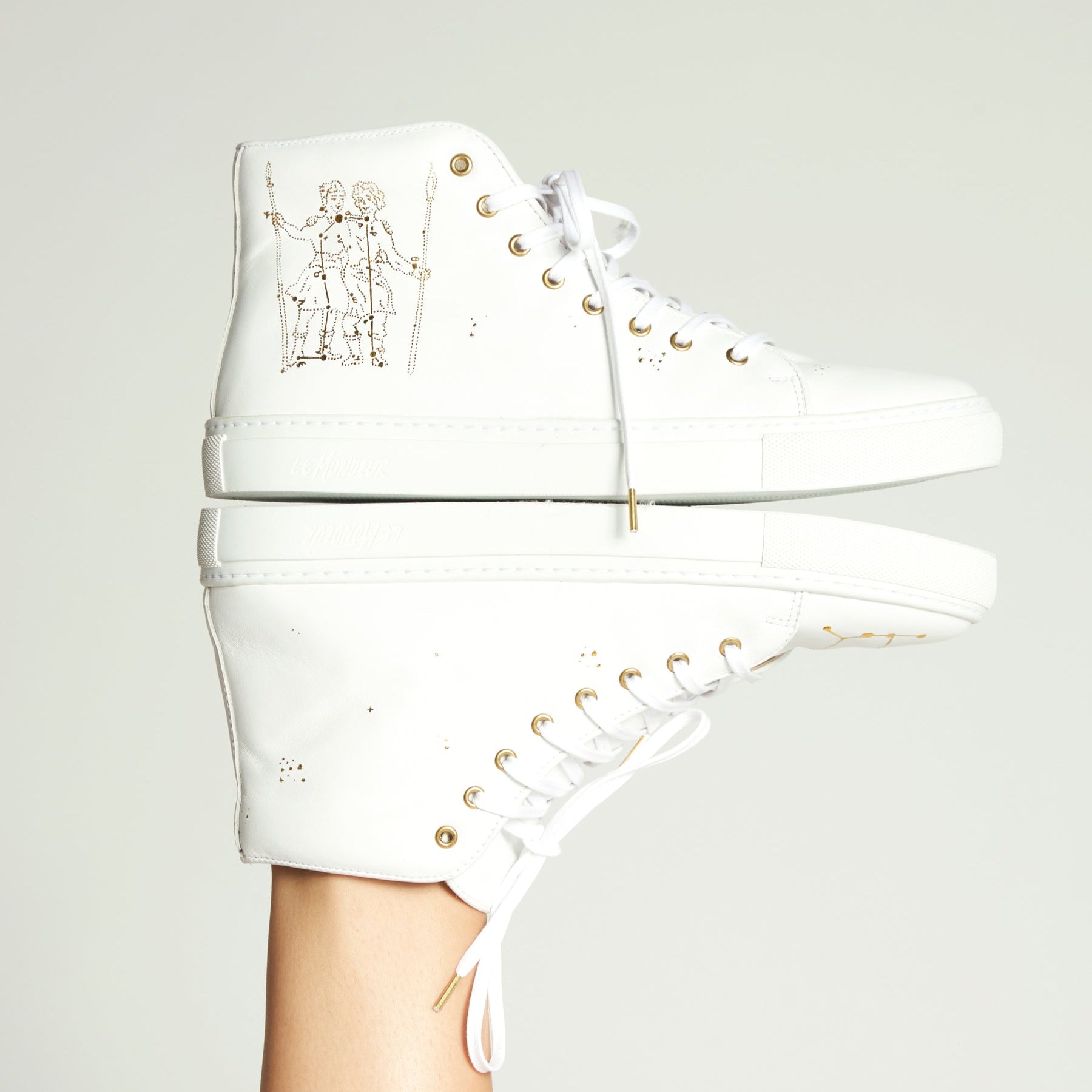 White high-top sneakers with gold accents on a light gray background